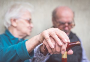 Couple de personne âgé main dans la main avec une canne