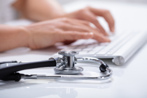 Docteur avec son stéthoscope qui tape sur son clavier d'ordinateur